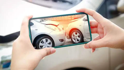 A person holding a smartphone looking at the documentation of a car accident